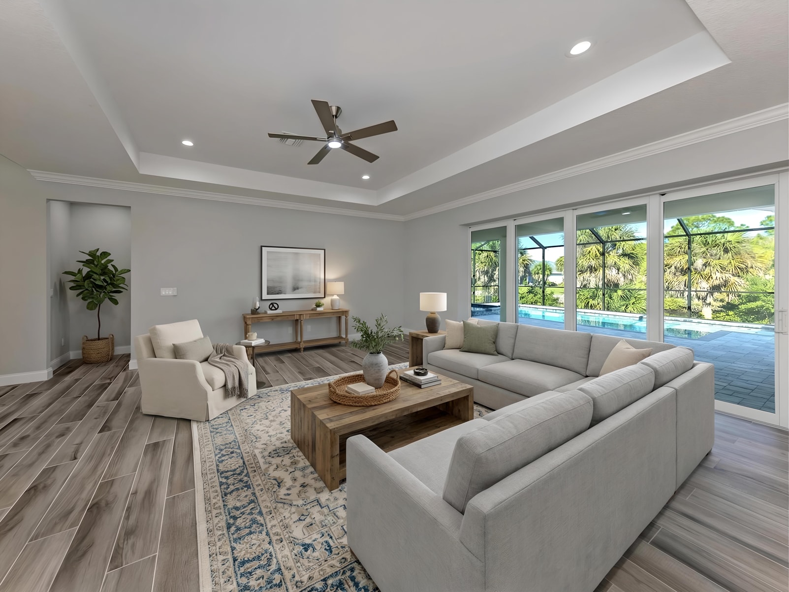 Open living room with pool views and tray ceiling
